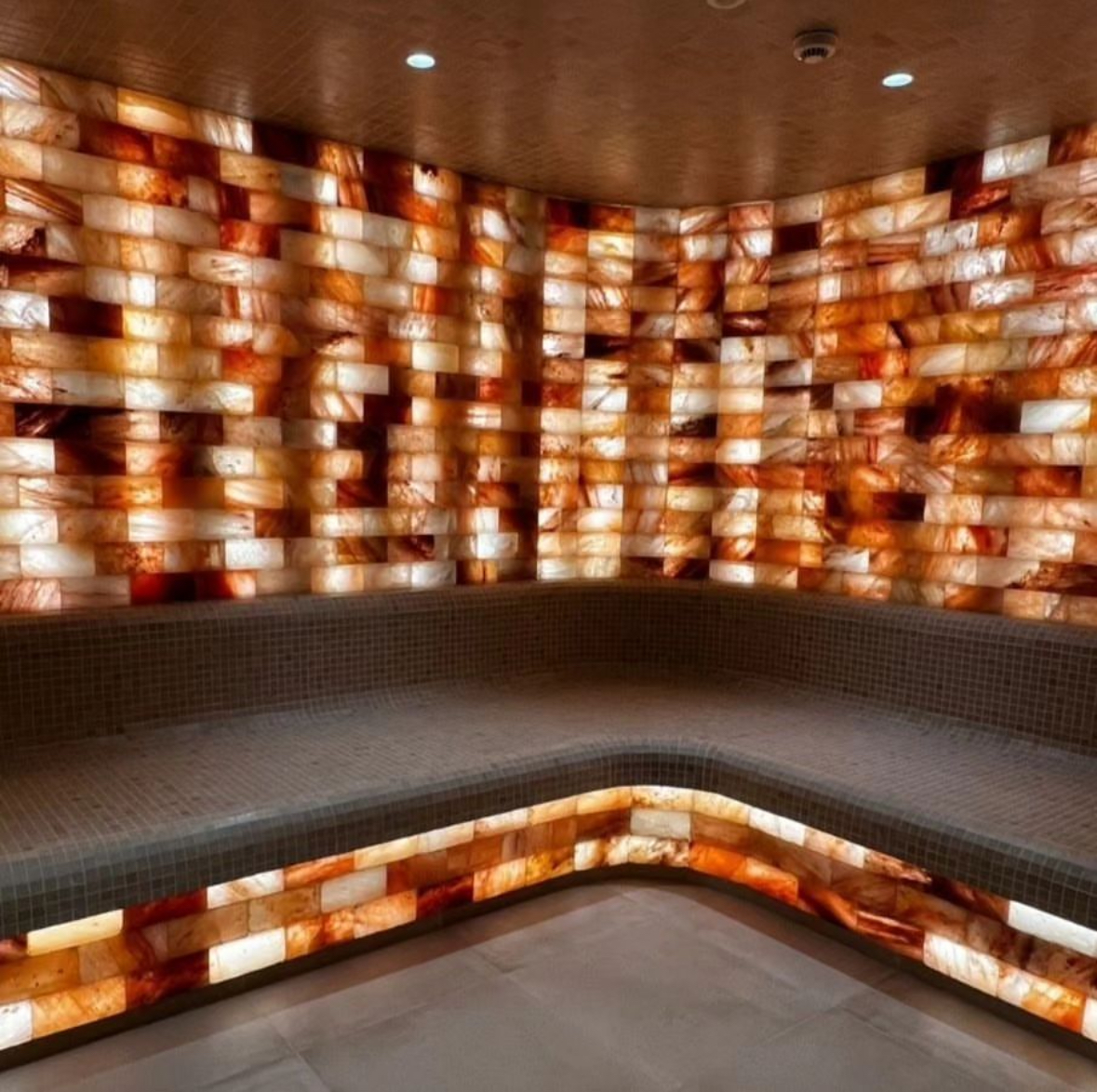 A sauna in Tips and Toes with glowing orange salt walls and a curved bench.