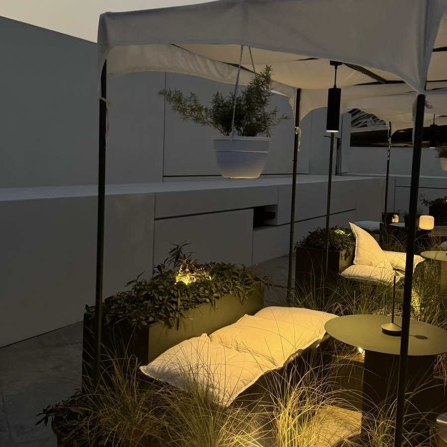 A view of the rooftop furniture and decor, surrounded by vibrant greenery and plants. This Instagrammable cafe in Abu Dhabi offers a serene environment for guests, blending natural elements with stylish, modern design for a relaxed, aesthetic atmosphere